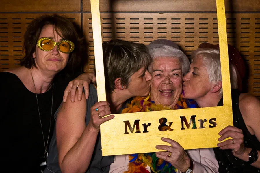Invitées de plusieurs générations posant avec un cadre Mr and Mrs
